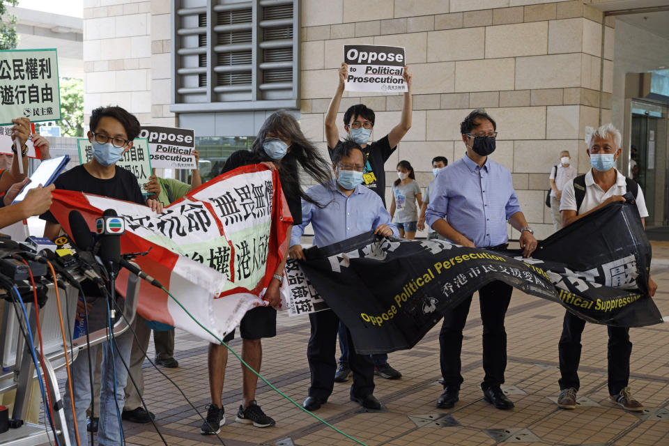 Pro-democracy activists including Leung Kwok-hung, second left, hold banners outside a district court in Hong Kong, Thursday, July 30, 2020. Activists including Lai who organized the June 4th Tiananmen massacre memorial this year, which was banned by police because of anti-virus social distancing reasons, appeared in a Hong Kong court on Monday on charges of inciting others to participate in an unlawful assembly. (AP Photo/Kin Cheung)