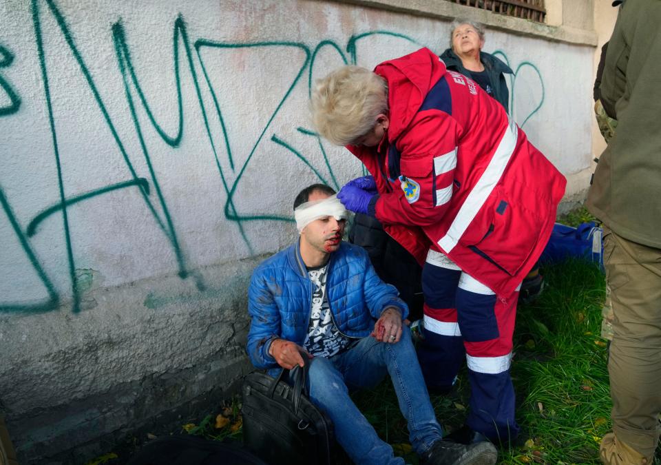 People receive medical treatment on the scene of Russian shelling in Kyiv, Ukraine, Monday, Oct. 10, 2022. Two explosions rocked Kyiv early Monday following months of relative calm in the Ukrainian capital.