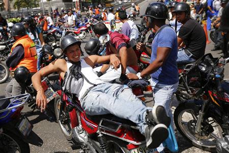 A motorcyclist rests on his motorbike as he takes part in a protest against possible regulation and schedule bans as a measure to combat insecurity in Caracas January 31, 2014. REUTERS/Jorge Silva