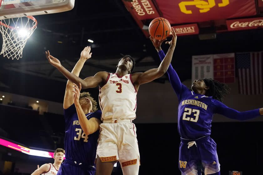 Southern California forward VIncent Iwuchukwu (3) works for a rebound between Washington center Braxton Meah.