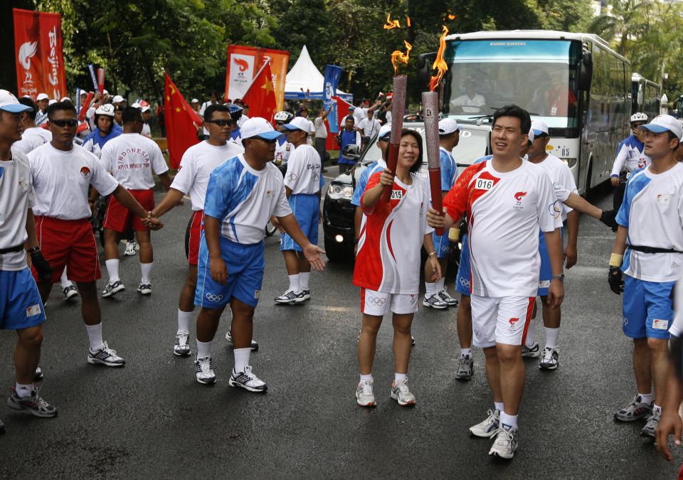 印尼羽毛球選手兼奧運金牌得主夫婦王蓮香 (左) 和魏仁芳 (右) 於 2008 年 4 月 22 日北京奧運會火炬傳遞期間在雅加達開始接力傳遞奧運火炬。   REUTERS/Beawiharta