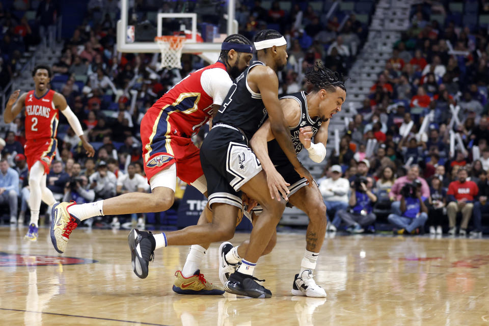 New Orleans Pelicans forward Brandon Ingram (14) collides with San Antonio Spurs guards Blake Wesley (14) and Tre Jones (33) while reaching for the ball in the first half of an NBA basketball game in New Orleans, Tuesday, March 21, 2023. (AP Photo/Tyler Kaufman)
