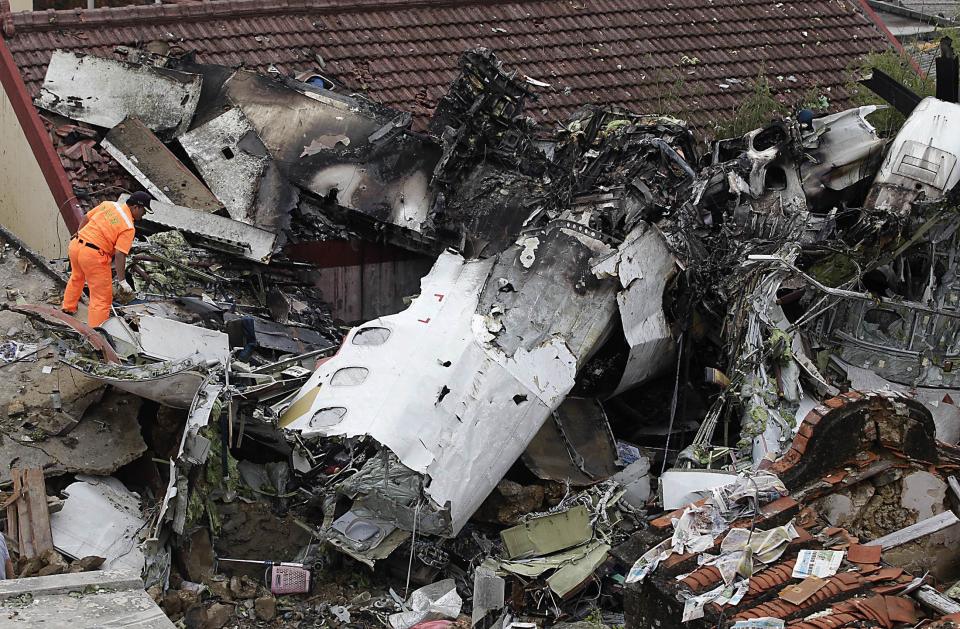 Rescue personnel survey the wreckage of a TransAsia Airways turboprop plane that crashed, on Taiwan's offshore island Penghu July 24, 2014. The leaders of rivals China and Taiwan expressed condolences on Thursday for victims of the plane that crashed during a thunderstorm the previous day killing 48 people including two French nationals. (REUTERS/Pichi Chuang)