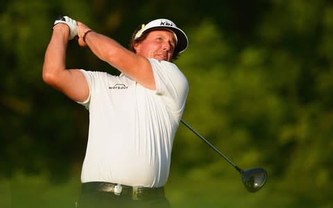 Phil Mickelson of the United States plays his shot from the 12th tee during the continuation of the weather delayed second round - Credit: Getty