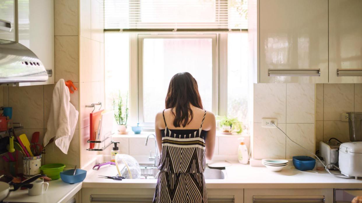 A teenage girl washing dishes in kitchen