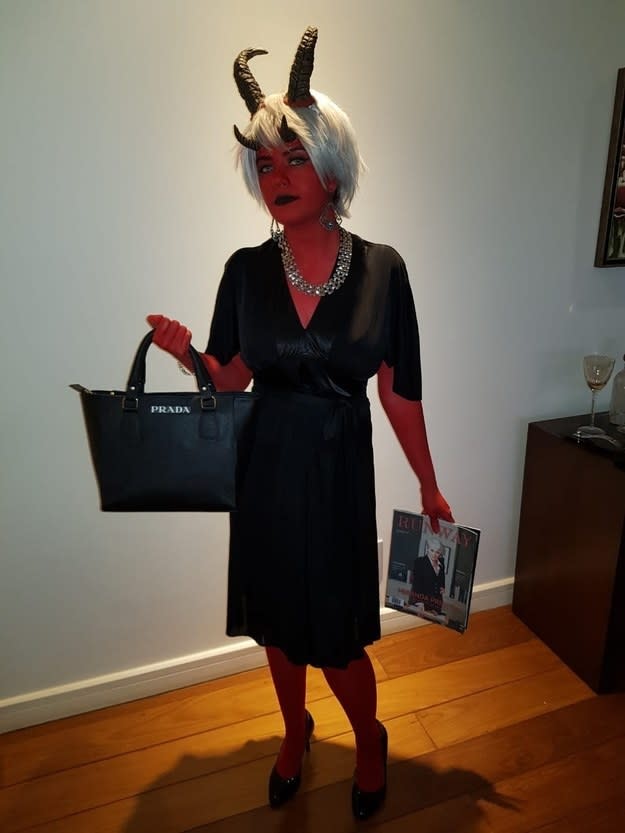 A woman dressed as the devil while holding a Prada bag