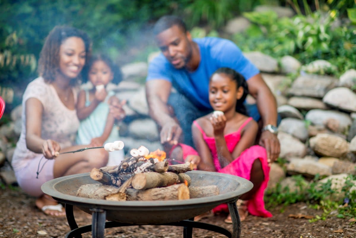 Family roasting marshmallows in fire pit