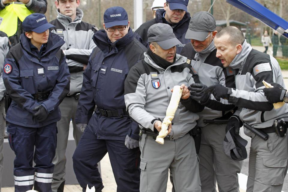 French Customs officers examine a carved elephant tusk, before crushing about 698 elephant tusk into dust, at the foot of the Eiffel Tower in Paris, Thursday Feb. 6, 2014. France is crushing more than 3 tons of illegal ivory in Europe's first destruction of a stockpile of the banned elephant tusks. Thursday's pulverization is intended to send a message to poachers and traffickers that preservationists hope will help stem the illicit trade that endangers the species' survival. (AP Photo/Remy de la Mauviniere)