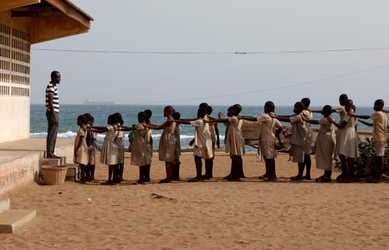 Pupils line up in the yard of their school, which was damaged by sea storms, in Baguida