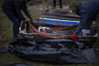 CAPTION CORRECTS LOCATION -Volunteers put in a bag the body of a civilian killed by Russian army, after been removed from a mass grave, during an exhumation in Mykulychi, Ukraine on Sunday, April 17, 2022. All four bodies in the village grave were killed on the same street, on the same day. Their temporary caskets were together in a grave. On Sunday, two weeks after the soldiers disappeared, volunteers dug them up one by one to be taken to a morgue for investigation. (AP Photo/Emilio Morenatti)