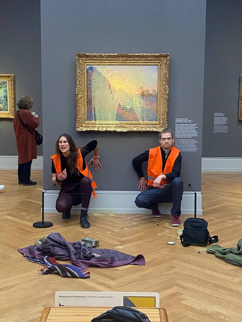 Last Generation activists glue themselves under a Claude Monet painting after throwing mashed potatoes onto the glass.