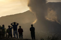 Residents look from a hill as lava continues to flow from an erupted volcano, on the island of La Palma in the Canaries, Spain, Friday, Sept. 24, 2021. A volcano in Spain’s Canary Islands continues to produce explosions and spew out lava, five days after it erupted. Two rivers of lava continue to slide slowly down the hillside of La Palma on Friday. (AP Photo/Emilio Morenatti)