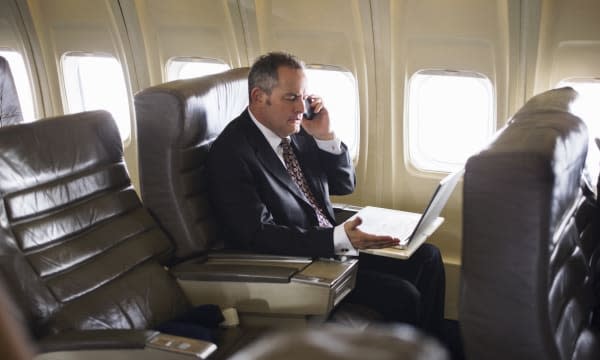 man wearing suit using cell phone on airplane