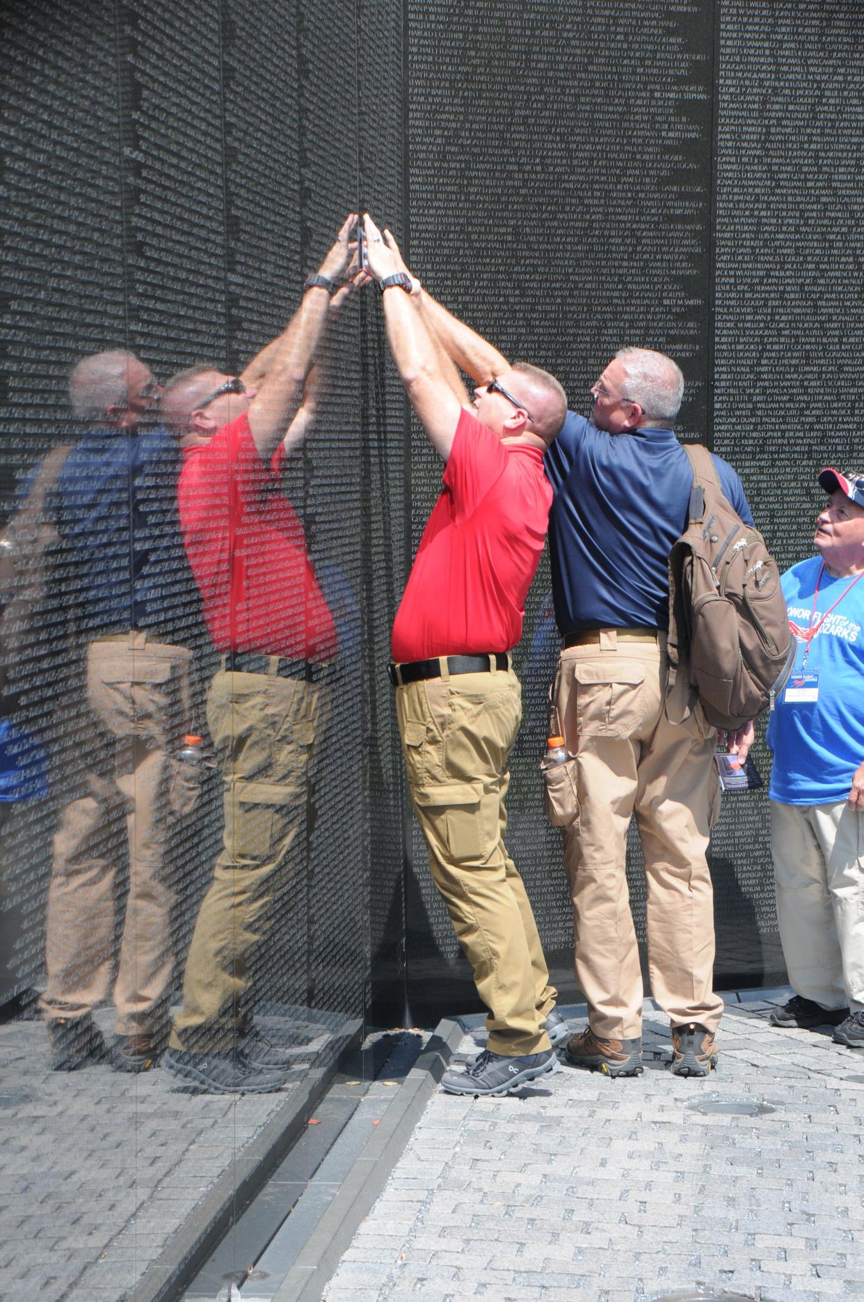 Honor Flight of the Ozarks flight coordinator David Snider (left) helps with the rubbing of a name at the Vietnam Memorial Wall during the Aug. 23, 2023 trip to Washington, D.C.