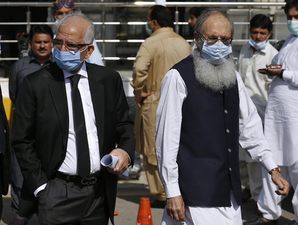 Ahmed Saeed Sheikh, right, father of a British-born militant Ahmed Omar Saeed Sheikh, leaves the Supreme Court with his lawyer Mahmood Ahmed Sheikh, left, after an appeal hearing in the Daniel Pearl case in Islamabad, Pakistan, Wednesday, Oct. 7, 2020. Ahmed Omar Saeed Sheikh, who has been on death row over the 2002 killing of U.S. journalist Daniel Pearl, will remain in jail for another three months under a government order, a prosecutor told the country's top court Wednesday, as it took up appeals of Pearl’s family and government against acquittal of all accused of murder charges by another court. (AP Photo/Anjum Naveed)