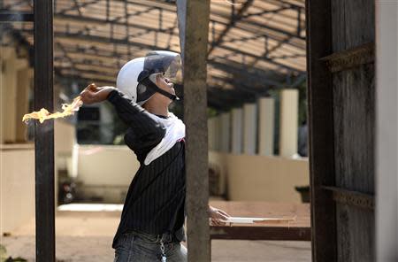 An anti-government protester throws a molotov cocktail at Thai riot police as they attack Government House in Bangkok December 1, 2013. REUTERS/Dylan Martinez