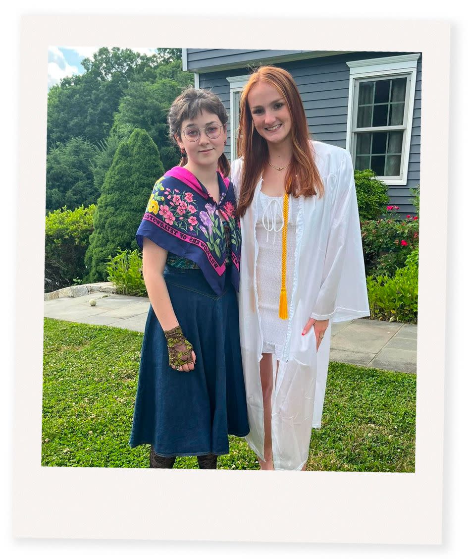 a couple of women posing for a picture in front of a house