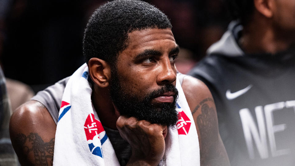 Kyrie Irving is pictured sitting on the Brooklyn Nets bench.