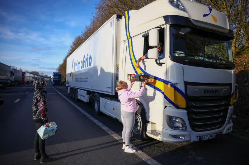 A woman hands out donated food to a lorry driver on the outskirts of Ashford