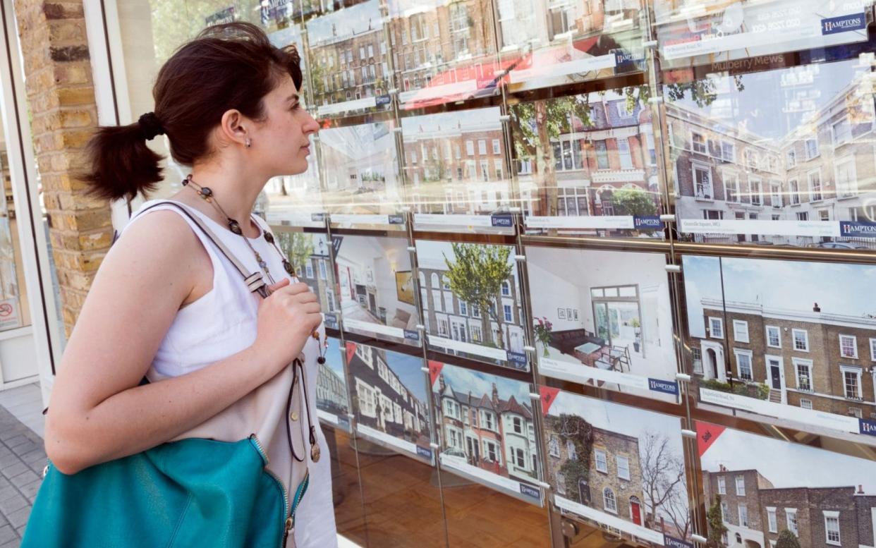 Young woman looking at houses for sale in estate agent window