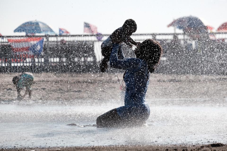 A mother and child in a fountain in Coney Island on a hot afternoon on July 06, 2023 in the Brooklyn borough of New York City.