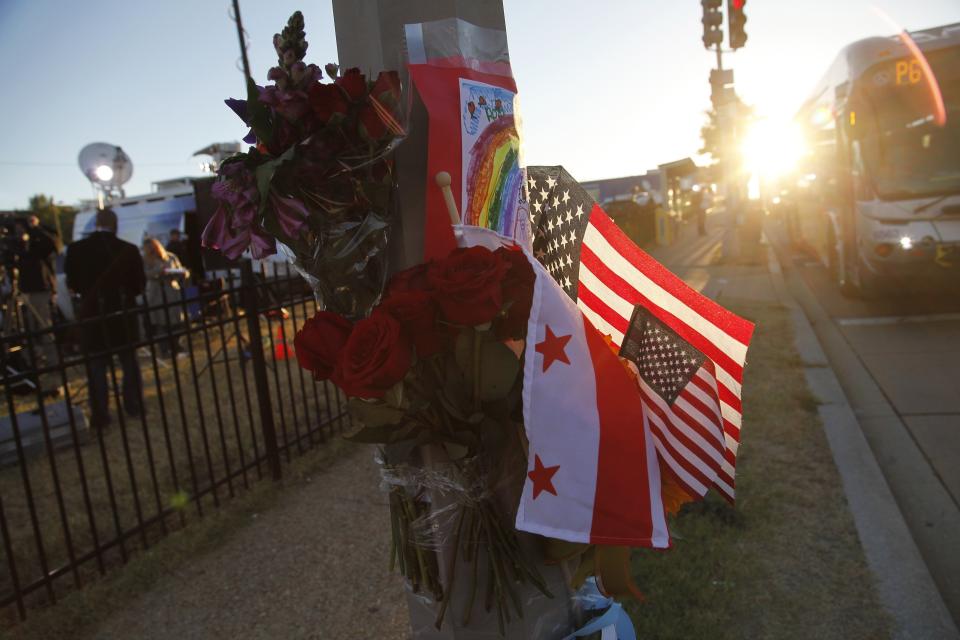 Flowers, flags and a child's drawing are pictured at a makeshift memorial outside the Navy Yard two days after a gunman killed 12 people before police shot him dead, in Washington, September 18, 2013. U.S. lawmakers are calling for a review into how Aaron Alexis, the suspected shooter in Monday's rampage at the Washington Navy Yard, received and maintained a security clearance, despite a history of violent episodes. (REUTERS/Jonathan Ernst)