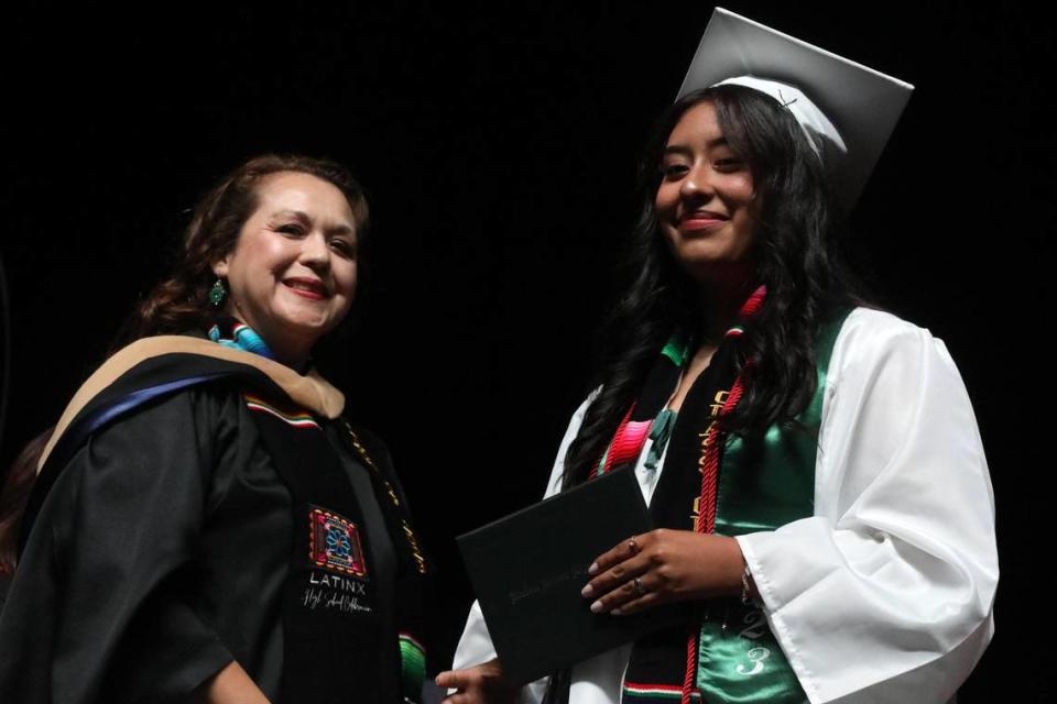 Una alumna de último año recibe su diploma de manos de Claudia Cázares, integrantes de la junta escolar, durante la ceremonia de graduación de Hoover High, celebrada en el Save Mart Center, el 6 de junio de 2023.