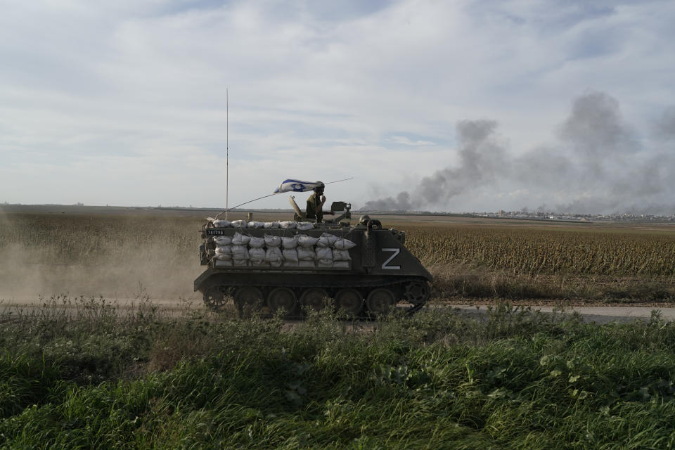 Israeli soldiers patrol as the smoke rises from the Gaza Strip after Israeli strikes on Saturday, Dec. 9, 2023. (AP Photo/Leo Correa)