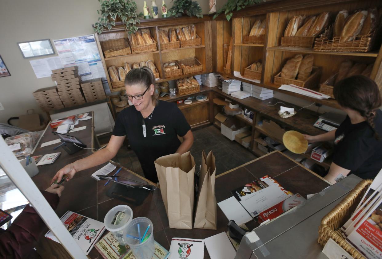 Rickie Leary waits on a customer as she and staff fill orders at the counter at Giuseppe's in Gates Thursday, March 3, 2022.