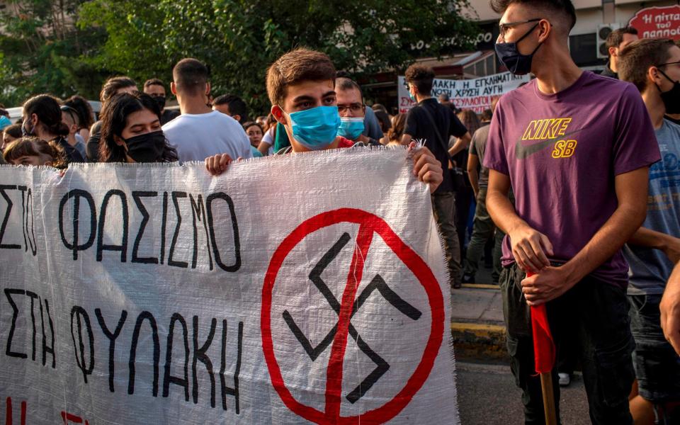 Protesters hold a banner with a logo of Nazi swastika during a protest on the day of the verdict in the trial of suspected members of neo-Nazi party Golden Dawn - ANGELOS TZORTZINIS /AFP