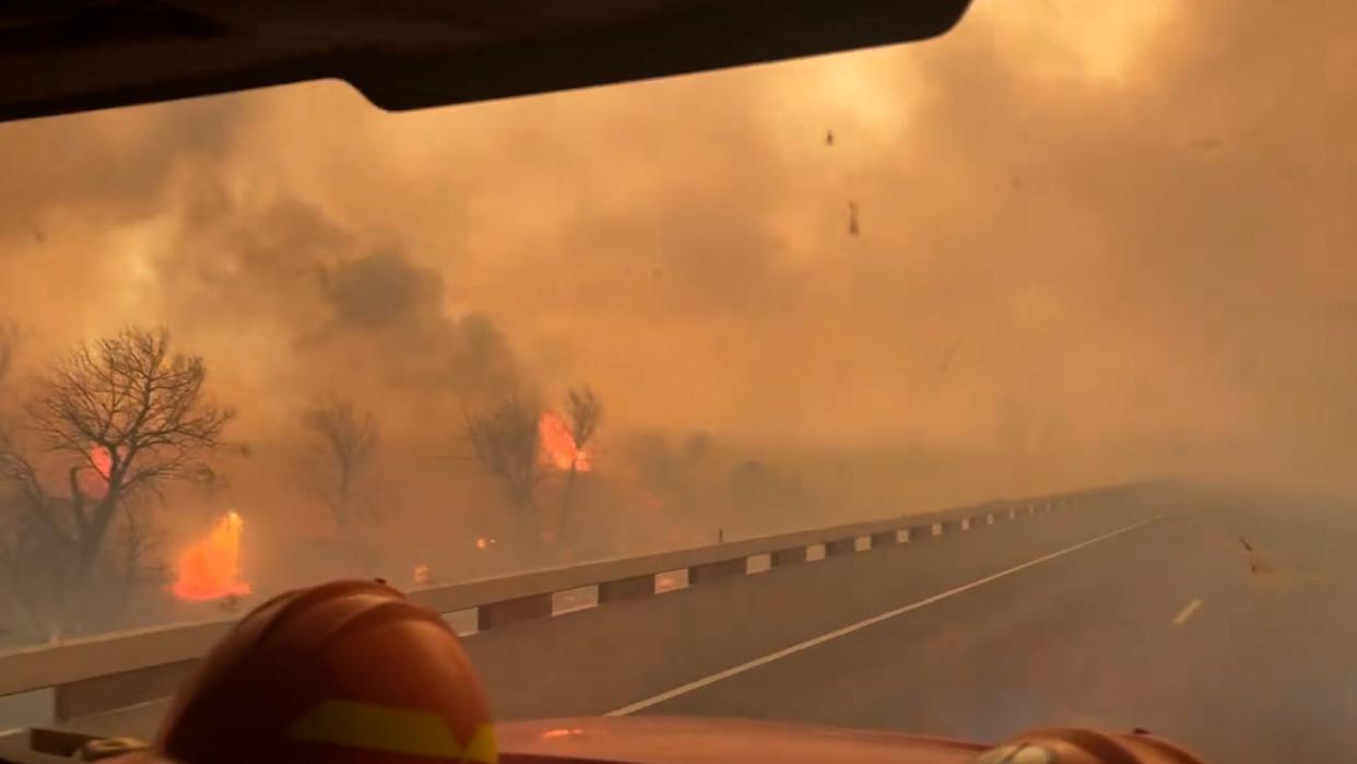 Smoke engulfs a Texas roadway as firefighters maneuver themselves to help put of the flames.