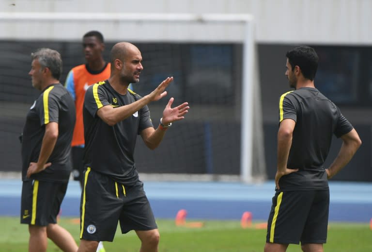 Manchester City coach Pep Guardiola (L) speaks with coaching staff during a training session in Beijing on July 24, 2016, the day before the 2016 International Champions Cup match against Manchester United