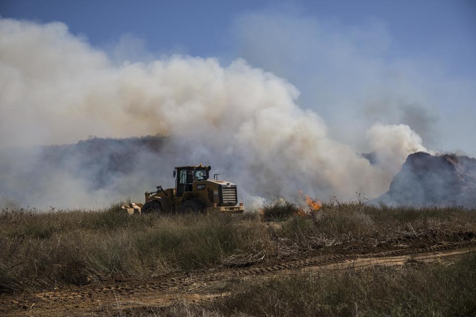 FILE - In this June 20, 2018 file photo, an Israeli tractor extinguishes a fire started by a kite with attached burning cloth launched by Palestinians from Gaza, on the Israel and Gaza border. Hamas officials say Egypt is trying to broker a broad new cease-fire deal between Gaza’s ruling group and Israel to pave the way for Gaza's reconstruction and an eventual prisoner swap. Repeated cease-fire deals over the years collapsed, but there were signs Thursday, Aug. 2, 2018, of possible momentum toward a new agreement, after weeks of escalation between Israel and Hamas. (AP Photo/Tsafrir Abayov, File)