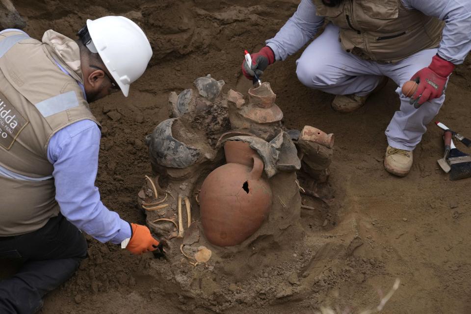 Archaeologists uncover bones and vessels discovered by city workers who were digging a natural gas line for the company Calidda in the district of Carabayllo on the outskirts of Lima, Peru, Friday, Sept. 22, 2023. Eight burial offerings from the pre-Inca Ychsma culture have been identified by archeologists so far, according to lead archeologist Jesus Bahamonde. (AP Photo/Martin Mejia)