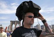 FILE - In this July 24, 2016, file photo German tourist Guido Weber of Hanover uses his backpack to cover his head against the hot afternoon sun after forgetting to wear his hat as he walks across the Brooklyn Bridge in New York. For the third straight year, Earth set a record for the hottest year, NOAA and NASA announced. NASA says 2016 was warmer than 2015 - by a lot. It's mostly global warming with a little assist from the now-gone El Nino. (AP Photo/Kathy Willens, file)