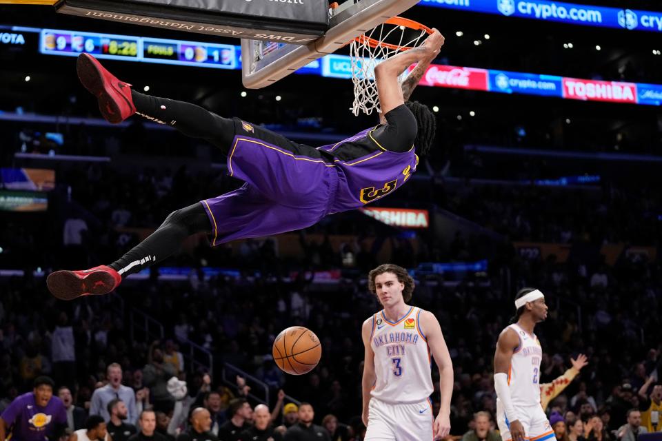 Lakers forward Anthony Davis dunks as Thunder guard Josh Giddey (3) and guard Shai Gilgeous-Alexander look on during the first half of Friday's game at Crypto.com Arena in Los Angeles.