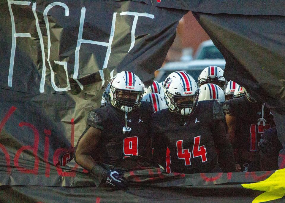 Pike Road's Malik Blocton (9) and Khurtiss Perry (44)peak out from the team banner before kickoff at home against Andalusia on September 10, 2021. 