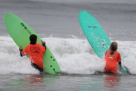 A surfer carries a Doyle surfboard in Malibu