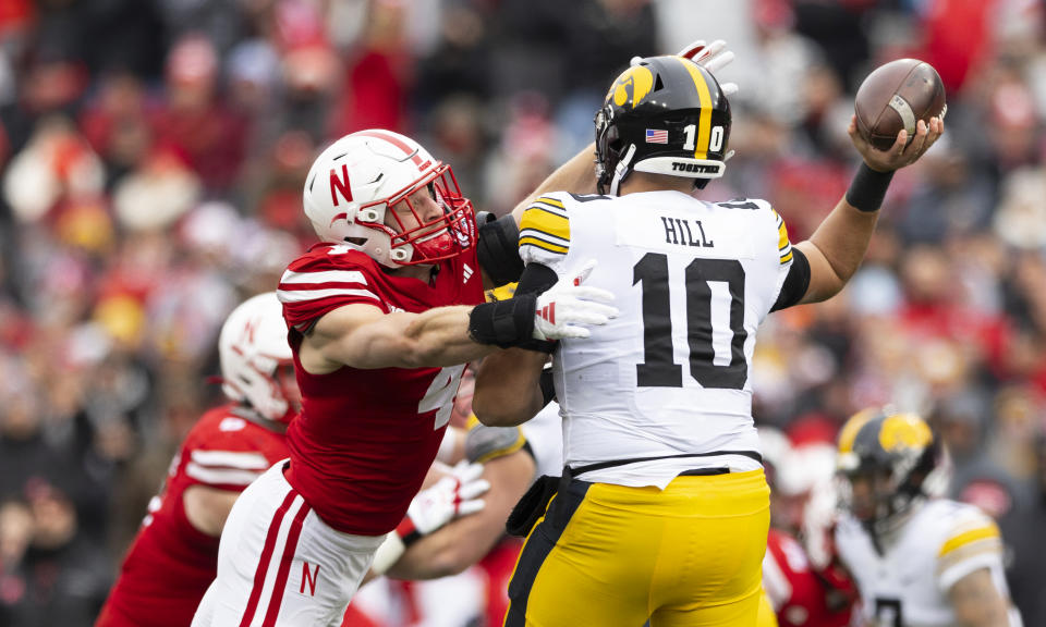 Iowa quarterback Deacon Hill (10) passes the ball while under pressure from Nebraska's Luke Reimer (4) during the first half of an NCAA college football game Friday, Nov. 24, 2023, in Lincoln, Neb. (AP Photo/Rebecca S. Gratz)