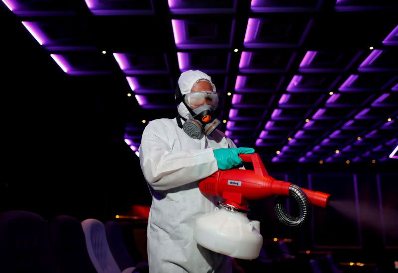 Worker sprays disinfectant inside theatre before Miss International Queen beauty pageant in Pattaya