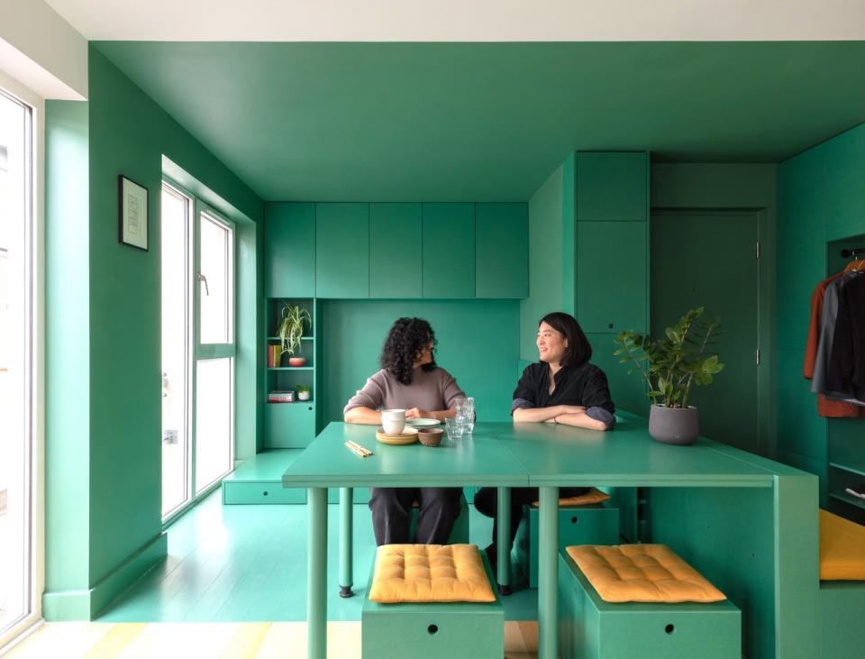 Homeowner Helen Zhou and another woman sitting in her studio apartment in London.