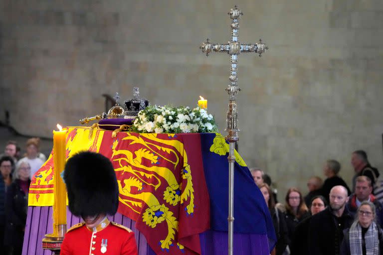 El ataúd de la Reina Isabel II, envuelto en el Estandarte Real con la Corona del Estado Imperial y el orbe y el cetro del Soberano, mientras los miembros del público pasan por Westminster Hall