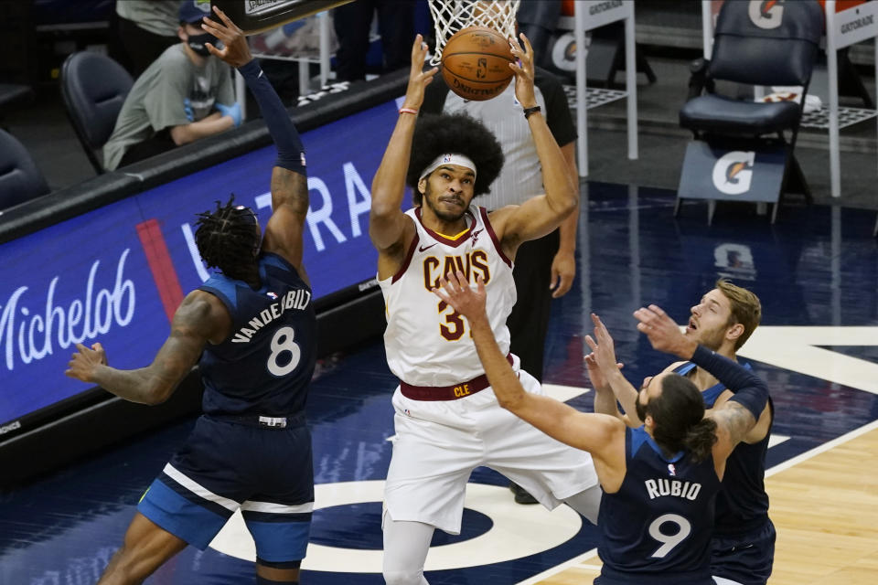 Cleveland Cavaliers' Jarrett Allen, center, beats Minnesota Timberwolves players, including Jarred Vanderbilt, left, and Ricky Rubio, right, to a rebound in the first half of an NBA basketball game Sunday, Jan. 31, 2021, in Minneapolis. (AP Photo/Jim Mone)