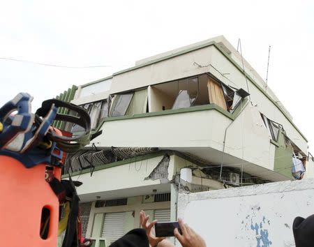 A person takes pictures of a damaged building after an earthquake struck off Ecuador's Pacific coast, at Tarqui neighborhood in Manta April 17, 2016. REUTERS/Guillermo Granja