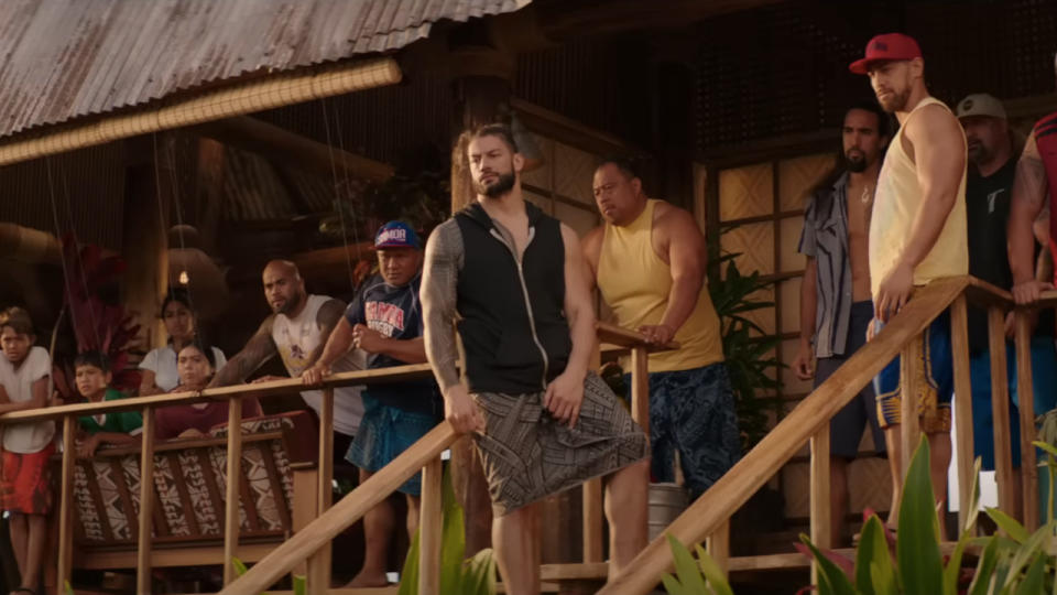 Roman Reigns stands on the porch stairs, surrounded by other Hobbs family members, in Fast and Furious Presents: Hobbs and Shaw.