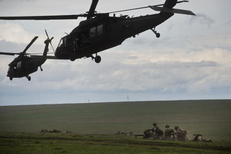 British servicemen under US Army choppers during NATO military exercise on April 21, 2015 in Smardan, Romania