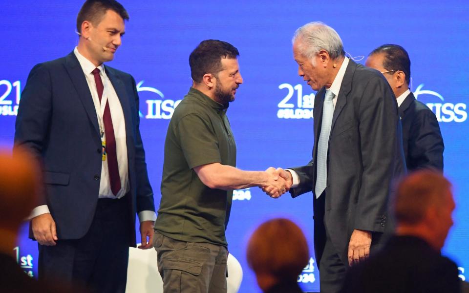 Volodymyr Zelensky shakes hands with Singapore's defence minister Ng Eng Hen