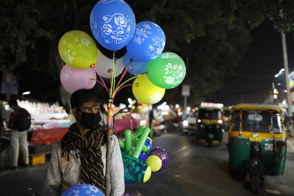 A balloon seller wearing a face mask as a precaution against coronavirus waits for customers in New Delhi India, Saturday, Nov. 7, 2020. (AP Photo/Rajesh Kumar Singh)
