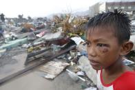 RNPS - PICTURES OF THE YEAR 2013 - A boy who was wounded by flying debris due to Super Typhoon Haiyan stays at the ruins of his family's house in Tacloban city November 10, 2013. Haiya, one of the most powerful storms ever recorded killed at least 10,000 people in the central Philippines province of Leyte, a senior police official said on Sunday, with coastal towns and the regional capital devastated by huge waves. Super typhoon Haiyan destroyed about 70 to 80 percent of the area in its path as it tore through the province on Friday, said chief superintendent Elmer Soria, a regional police director. REUTERS/Erik De Castro (PHILIPPINES - Tags: DISASTER ENVIRONMENT TPX)