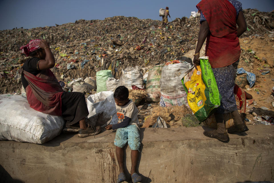 Imradul Ali, 10, left, and his mother Anuwara Beghum, 30, take a break as they look for recyclable material at a landfill on the outskirts of Gauhati, India, Thursday, Feb. 4, 2021. Once school is done for the day, Ali, rushes home to change out of his uniform so that he can start his job as a scavenger in India’s remote northeast. Coming from a family of scavengers or “rag pickers," Ali started doing it over a year ago to help his family make more money. Ali says he doesn’t want to spend his life doing this, but he doesn’t know what the future holds. (AP Photo/Anupam Nath)